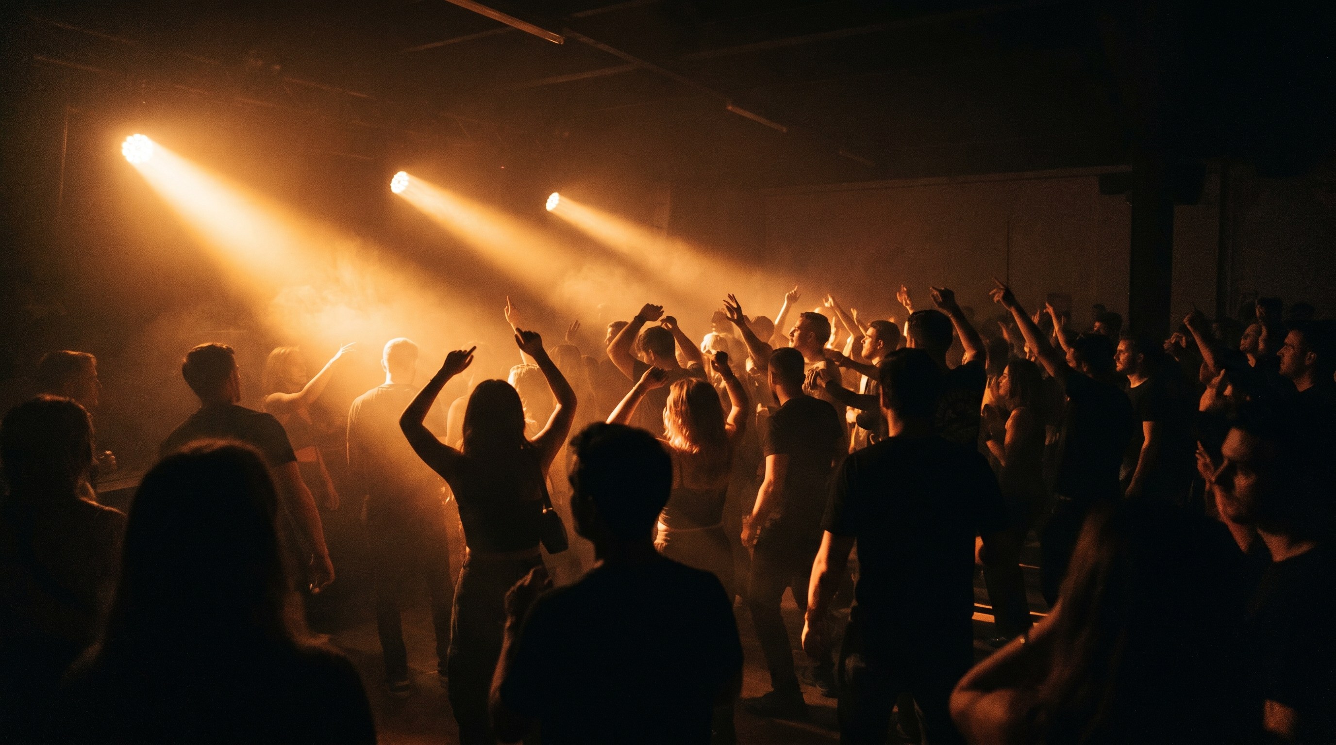 Intimate club dancefloor with crowd dancing in warm amber light